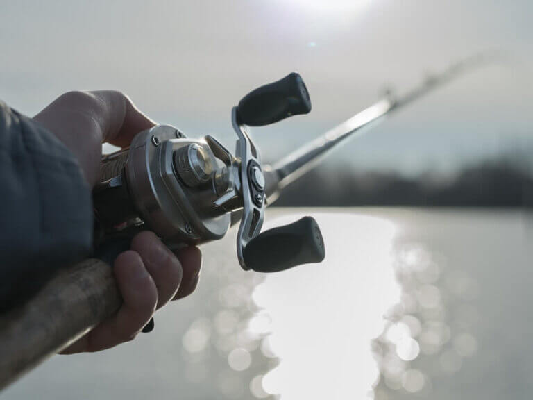 Angler on the river with close up baitcasting reel in hilights